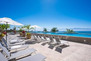 a row of chairs and umbrellas next to a swimming pool at Beachfront townhouse TH03A in Cruz de Huanacaxtle