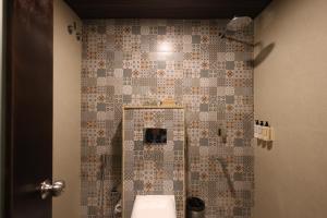 a bathroom with a toilet and a tiled wall at Ved Mahal in Jaipur