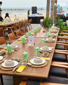 a long wooden table with plates and napkins on a beach at CASA Villa NOVAWORLD Phan Thiet in Phan Thiet