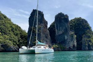 a boat sitting in the water in front of cliffs at Croisière dans les îles de Krabi in Ao Nang Beach