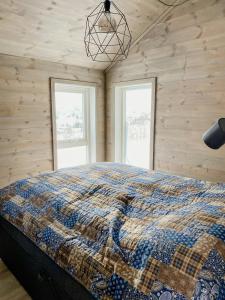 a bed in a room with wooden walls and windows at Mountain Cabin With Glacier Views in Norheimsund