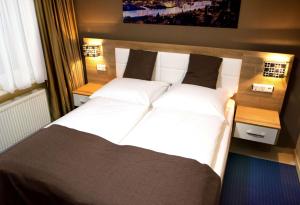 a bedroom with a large bed with white sheets at C&S Hotel in Pinneberg