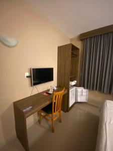 a hotel room with a desk with a television and a bed at Hotel Abba Goiana PE in Goiana