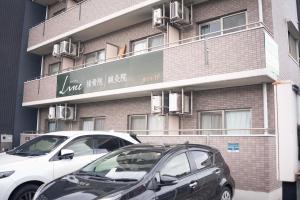 zwei Autos parkten vor einem Gebäude in der Unterkunft 宿Luce in Okayama