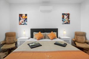 a bedroom with a large bed with two chairs at Harborview Modern Studio 11F in Victor Harbor