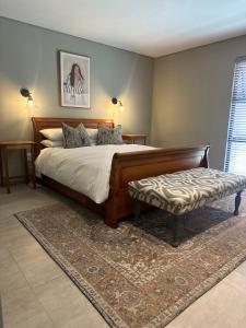 a bedroom with a large bed and a bench at Fallen Oak Villa 2 in George