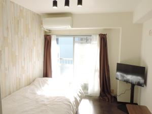 a bedroom with a bed and a window at フレクション大工町 in Miyazaki