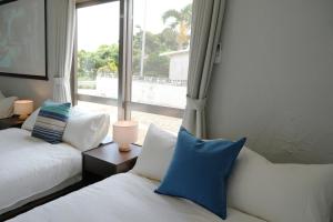 a bedroom with two beds and a large window at Retreat Ginoza in Ginoza