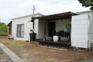 a white house with a porch with a table at Retreat Ginoza in Ginoza