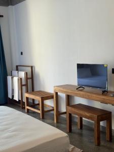 a room with a tv and a table and benches at Cielo Hiriketiya in Hiriketiya