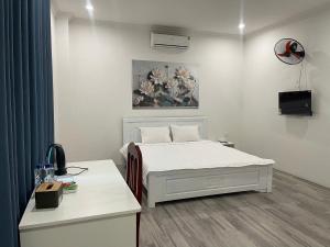 a bedroom with a white bed and a painting on the wall at Nice's Hotel Ninh Binh in Ða Gia