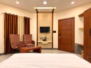 a bedroom with a bed and two chairs and a television at Krishnam Resort in Jabalpur