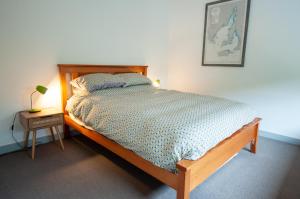 a bedroom with a bed with a wooden frame and a table at Eco Retro Aldinga Beach House in Aldinga Beach