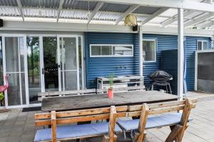a blue house with a wooden table and chairs at Eco Retro Aldinga Beach House in Aldinga Beach