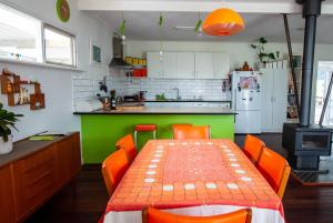 a kitchen with a table with orange chairs and a green counter at Eco Retro Aldinga Beach House in Aldinga Beach +6 photos
