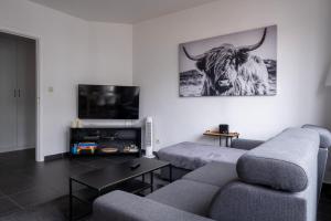 a living room with a couch and a cow on the wall at Appartement Ann in Blankenberge