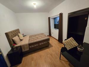 a bedroom with a bed and a couch and a chair at Magnolia Andina Hotel in Cusco