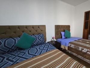 a bedroom with two beds with blue and green pillows at Magnolia Andina Hotel in Cusco