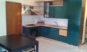 - une cuisine avec des placards bleus, un évier et une table dans l'établissement Le Torri Apartments, à Pérouse