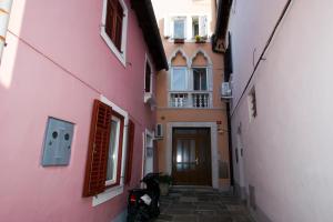 an alley with a scooter parked next to a pink building at Apartment Perc in Koper