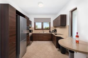 a kitchen with a stainless steel refrigerator and a table at Villa Leyland in Faliraki +11 photos