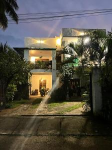 a white house with a palm tree in front of it at Green Sapphire Home Stay in Anuradhapura