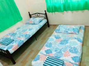 two beds in a room with green curtains at Olympia Travellers INN in Looc +28 photos
