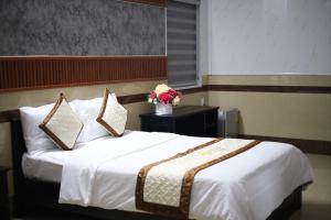 a bedroom with a white bed with a vase of flowers at Bảo Cường Hotel in Hương Hóa
