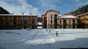um parque de estacionamento coberto de neve em frente a alguns edifícios em Apartmán Medvědín 110 em Spindleruv Mlyn