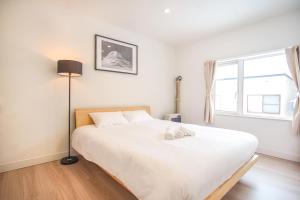 a bedroom with a white bed with a lamp and a window at Grouse Lodge -5 mins to ski field by walk- in Furano