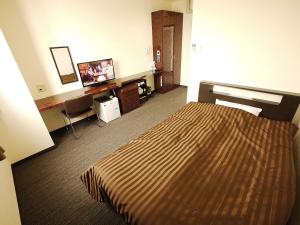 a hotel room with a bed and a flat screen tv at Business Hotel Fiz Nagoya Airport in Toyoyama