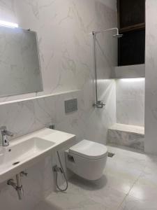 a white bathroom with a toilet and a sink at New Apartment in Islamabad