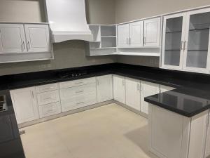 a kitchen with white cabinets and a black counter top at New Apartment in Islamabad