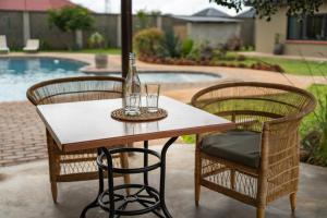 a table with two chairs and a bottle on it at The Drift Cottage in Livingstone +6 photos