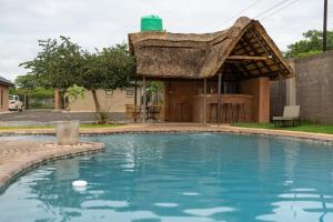 a thatch roof house with a swimming pool at The Drift Cottage in Livingstone