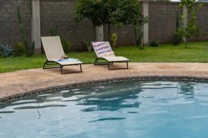 two chairs sitting next to a swimming pool at The Drift Cottage in Livingstone