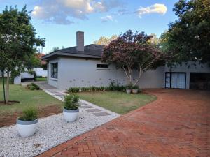 a white house with a brick driveway at Kinn Accommodation in Bloemfontein