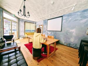a woman sitting at a wooden table in a room at Kaido Urasa CoLiving in Minami Uonuma