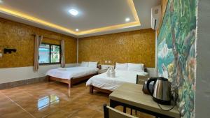 a hotel room with two beds and a table at Baan Gamnan Resort Krabi in Ban Khao Ngam