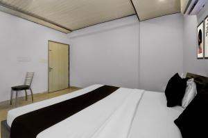 a bedroom with a white bed and a chair at Collection O Saral Bihari Temple Formerly Black Panther in Sheodāspura