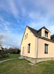 an old house in a field with a blue sky at Charmante maison moderne et cosy in Aunay-sur-Odon