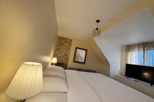 a bedroom with a large white bed and a flat screen tv at Charmante maison moderne et cosy in Aunay-sur-Odon