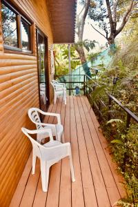 a wooden deck with two chairs and a table at Cabaña Colibrí - Parking in Sarchí
