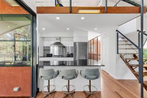 a kitchen with a counter and two stools at Sunsets on Kalang in Urunga +7 photos