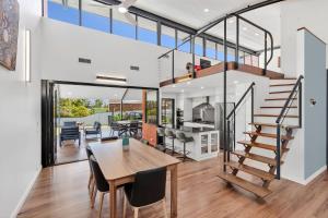 a dining room and kitchen with a staircase and a dining table at Sunsets on Kalang in Urunga