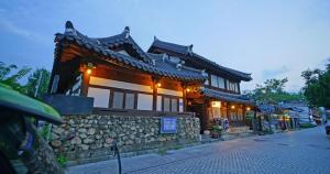 a building on a street with a stone wall at Jeonju Hanok Agbae in Jeonju