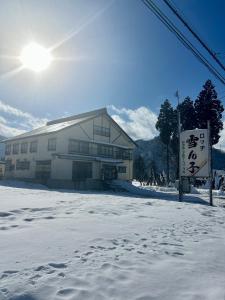 a building in the snow with a sign in front of it at ロッヂ 雪ん子 in Yuzawa