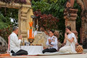a group of three people sitting on the ground praying at La Résidence Phou Vao in Luang Prabang