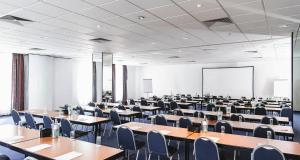 a large room with tables and chairs and a screen at PLAZA INN Grevenbroich in Grevenbroich