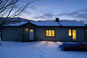 a house with its lights on in the snow at A pearl in Lofoten in Leknes